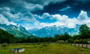 Majestuoso mirador de los Picos de Europa con nubes dramáticas sobre picos nevados y un prado verde.