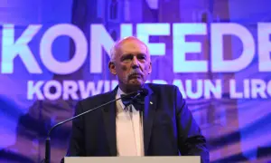 Janusz Korwin-Mikke, znany z kontrowersyjnych poglądów, przemawia na tle napisu "Konfederacja".