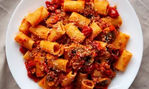 Pyszny obiad z mięsa mielonego z makaronem rigatoni w sosie pomidorowym, posypany parmezanem.