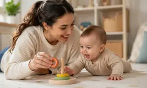 Madre sonríe a su bebé mientras juegan con un apilador de anillos, justo cuando empiezan a balbucear los bebés.