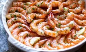 Gamberoni al forno succulenti, conditi con aglio e prezzemolo, pronti per essere gustati.