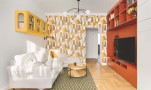 Jasny salon w stylu retro z białą kanapą, żółtą półką i pomarańczową zabudową RTV.