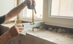 Ręce mierzą i poziomują miejsce pod montaż parapetów wewnętrznych.