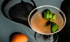 En läcker alkoholfri drink med basilika och en apelsinskal som dekoration.