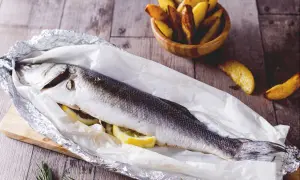 Gegrillter Seebarsch mit Zitrone, bereit für den köstlichen Geschmack. Dazu knusprige Kartoffelspalten.