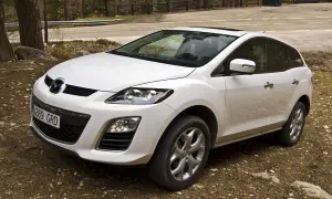 Biała Mazda CX7 zaparkowana na leśnej drodze.