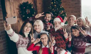 Wesoła rodzina robi sobie świąteczne stylizacje rodzinne selfie przy choince. Wszyscy pozdrawiają gestem pokoju.