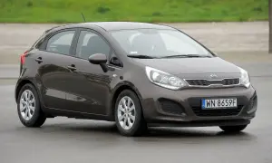 Brązowe kia rio 3 na mokrej nawierzchni, z widocznym numerem rejestracyjnym WN 8659F.