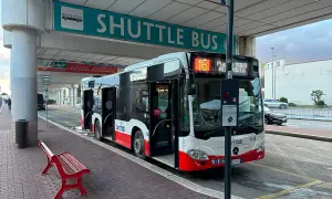 Autobus wahadłowy na przystanku lotnisko. Czerwona ławka czeka na pasażerów.