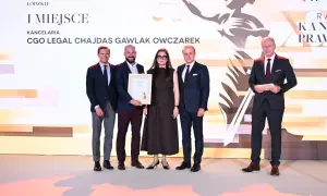Pięć osób w strojach formalnych pozuje do zdjęcia na tle sceny z grafiką przedstawiającą wagę sprawiedliwości.