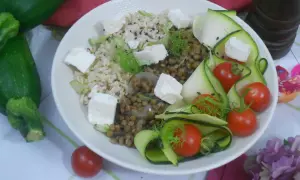 Salade de lentilles, riz, courgettes en rubans, tomates cerises et cubes de feta. Une assiette colorée et saine.