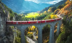 Czerwony pociąg Bernina Express przemierza malowniczy alpejski krajobraz jesienią. Sprawdź bernina express cena i zaplanuj podróż!
