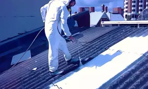 Trabajador con traje protector aplica pintura para uralita en un tejado.