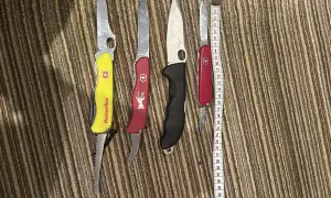 Cztery scyzoryki, w tym jeden z napisem "Rescue Tool", leżą obok miarki. Czy można przewozić nóż w bagażu rejestrowanym?
