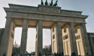 Das Brandenburger Tor, ein Meisterwerk der Klassizismus Architektur, mit seiner Quadriga auf dem Dach. Menschen spazieren davor.