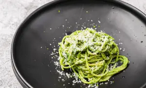 Ein Teller mit leckeren Nudeln mit Pesto, bestreut mit frisch geriebenem Parmesan.