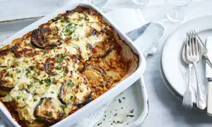 Un plat de moussaka végétarienne gratinée, garni d'aubergines et de persil frais, prêt à être dégusté.