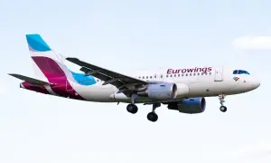 Samolot Eurowings z wysuniętym podwoziem na tle nieba.