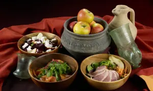 Essen wie im Mittelalter: Schalen mit Rote-Bete-Salat, Fleisch und Obst, dazu ein antiker Krug und Glas.
