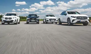 Białe i czarne SUV-y, w tym modele Mercedes, jadące po drodze.