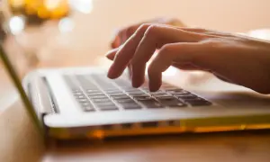 Mani che digitano su un laptop, con luci sfocate sullo sfondo. Un'istantanea del **mod ap 70** che cattura la concentrazione.