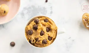 Leckeres Protein Cookie Dough Rezept in einer Tasse, mit Schokostückchen und auf einem Löffel mit Streuseln.