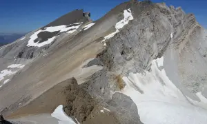 Vue spectaculaire d'une crête rocheuse et enneigée lors d'une barrhorn randonnée. Le ciel bleu azur domine.