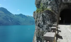 Sentiero panoramico per trekking a Riva del Garda, con vista sul lago e un tunnel scavato nella roccia.