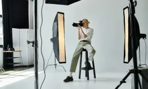 Młody fotograf w studiu z aparatem, zastanawia się, ile zarabia fotograf.