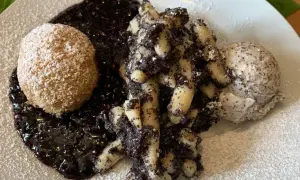 Gedrehte Nudeln mit Mohn, eine Kugel und Beerensoße, bestäubt mit Puderzucker.