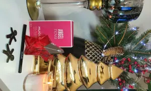 Świąteczna kompozycja z perfumami Angel Nova Mugler 50 ml, świecą, choinką i ozdobami.