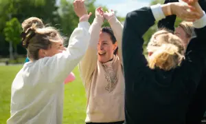 En grupp glada kollegor med armarna i luften, redo för roliga utmaningar på jobbet.