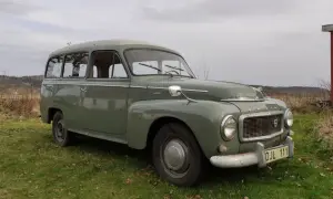 Grön Volvo P210 parkerad på en gräsmatta. Bilen har en klassisk design och ser ut att vara i gott skick.
