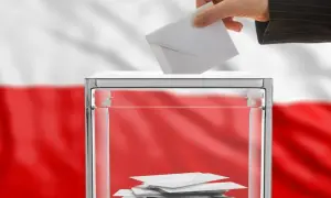 Dłoń wrzuca kartę do urny wyborczej. Polska flaga w tle symbolizuje kraj, od którego można głosować.