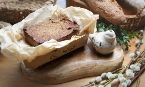 Pyszny pasztet z królika w papierowej foremce z zajączkiem, obok ceramiczny ptaszek i bazie.