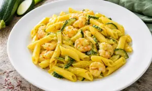 Piatto di pasta penne con zucchine e gamberetti, condito con una salsa cremosa e fili di zafferano.