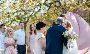 Nowoczesne błogosławieństwo: panna młoda tuli ojca, podczas gdy rodzina i świadkowie obserwują wzruszającą chwilę.