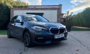 Un BMW Serie 1 116d gris aparcado frente a una casa con vegetación. A pesar de su aspecto, este modelo puede presentar problemas.