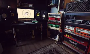 Profesjonalne domowe studio nagrań z monitorem, rackiem z efektami, wzmacniaczami Orange i Marshall, głośnikami studyjnymi i dywanem.