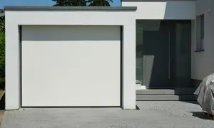 Moderne grenzbebauung mit weißer Garagentür und dunkler Eingangstür. Gepflasterte Einfahrt.