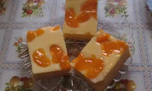 Drei Stücke faule weiber kuchen mit Mandarinen auf einem Tisch mit Blumenmuster.