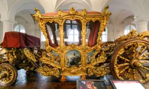 Prunkvolle Kutsche im Marstall Museum, vergoldet und mit Gemälden verziert, ein Zeugnis vergangener Pracht.