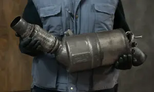 Mechanik w rękawiczkach trzyma zużyty element układu wydechowego, prawdopodobnie po problemach z wypalaniem DPF.