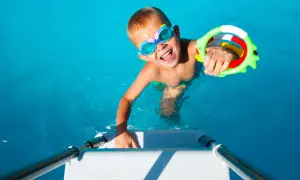 Niño feliz con gafas de buceo y un juguete de agua, listo para juegos en la piscina.