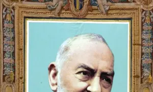 Portret Ojca Pio, jego ciało jest częściowo widoczne. Obraz ozdobiony jest bogatą ramą z motywami kwiatowymi i aniołkami.