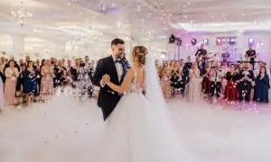 Para młoda tańczy na weselu, goście patrzą, zespół gra. W tle konfetti i dym. Piękny moment, ale czy wiesz o ukrytych kosztach wesela?
