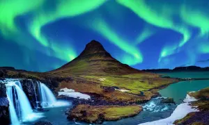 Spektakularna zorza polarna nad górą Kirkjufell, ikoną Islandii. Wodospad i rzeka dopełniają ten magiczny krajobraz.