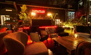 L'anima della birreria: poltrone accoglienti, piante rigogliose e luci al neon rosse creano un'atmosfera vibrante per la notte.