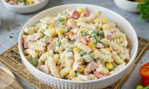 Ein cremiger nudelsalat mit mayonaise, Erbsen, Mais und Schinkenwürfeln. Perfekt für ein Picknick.