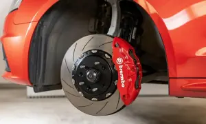 Gros plan sur un étrier de frein Brembo rouge vif sur une voiture de sport. Le disque de frein rainuré est visible. Idéal pour connaître le tarif changement étrier de frein.